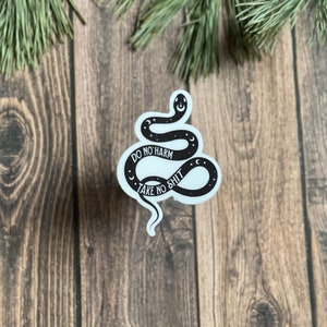 May include: White sticker with a black snake design. The snake is curled into a circle with the text "Do No Harm Take No Shit" inside the circle.