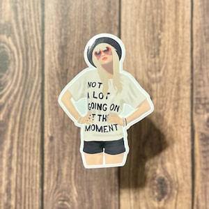 Peut inclure: Un t-shirt blanc avec du texte noir qui dit "Pas grand-chose &agrave; faire en ce moment". La personne sur l'image porte un chapeau noir, des lunettes de soleil rouges et un short noir.