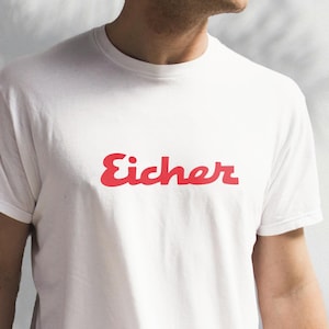 May include: White t-shirt with a red "Eicher" logo printed on the front.