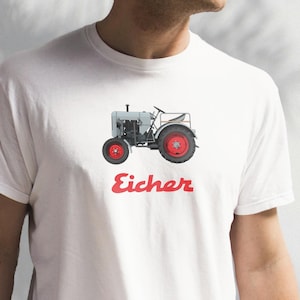 May include: White t-shirt with a gray and red illustration of a vintage tractor with the word "Eicher" in red.