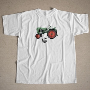 May include: White t-shirt with a green and red tractor illustration and the text "TL13" printed on the front.