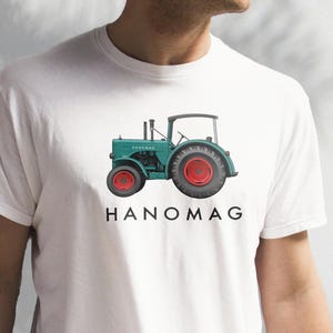 May include: White t-shirt with a green and red tractor illustration and the text "HANOMAG" printed on the front.