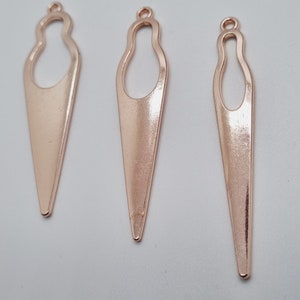Peut inclure: Trois breloques en métal doré rose en forme de cornet de glace avec une boucle en haut. Les breloques mesurent environ 5 cm de long.