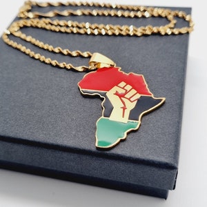 K&ouml;nnte beinhalten: Goldkette mit einem Anh&auml;nger in Form des afrikanischen Kontinents. Der Anh&auml;nger ist rot, schwarz und gr&uuml;n mit einer goldenen Faust, die in die Luft erhoben ist.