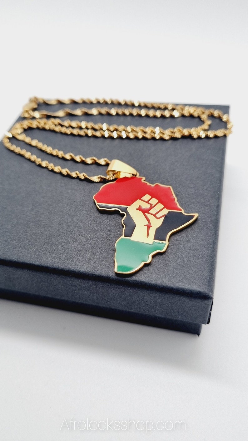 K&ouml;nnte beinhalten: Goldkette mit einem Anh&auml;nger in Form des afrikanischen Kontinents. Der Anh&auml;nger ist rot, schwarz und gr&uuml;n mit einer goldenen Faust, die in die Luft erhoben ist.