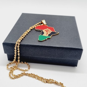 K&ouml;nnte beinhalten: Goldkette mit einem Anh&auml;nger in Form des afrikanischen Kontinents. Der Anh&auml;nger ist rot, gr&uuml;n und schwarz mit einer erhobenen Faust in der Mitte.