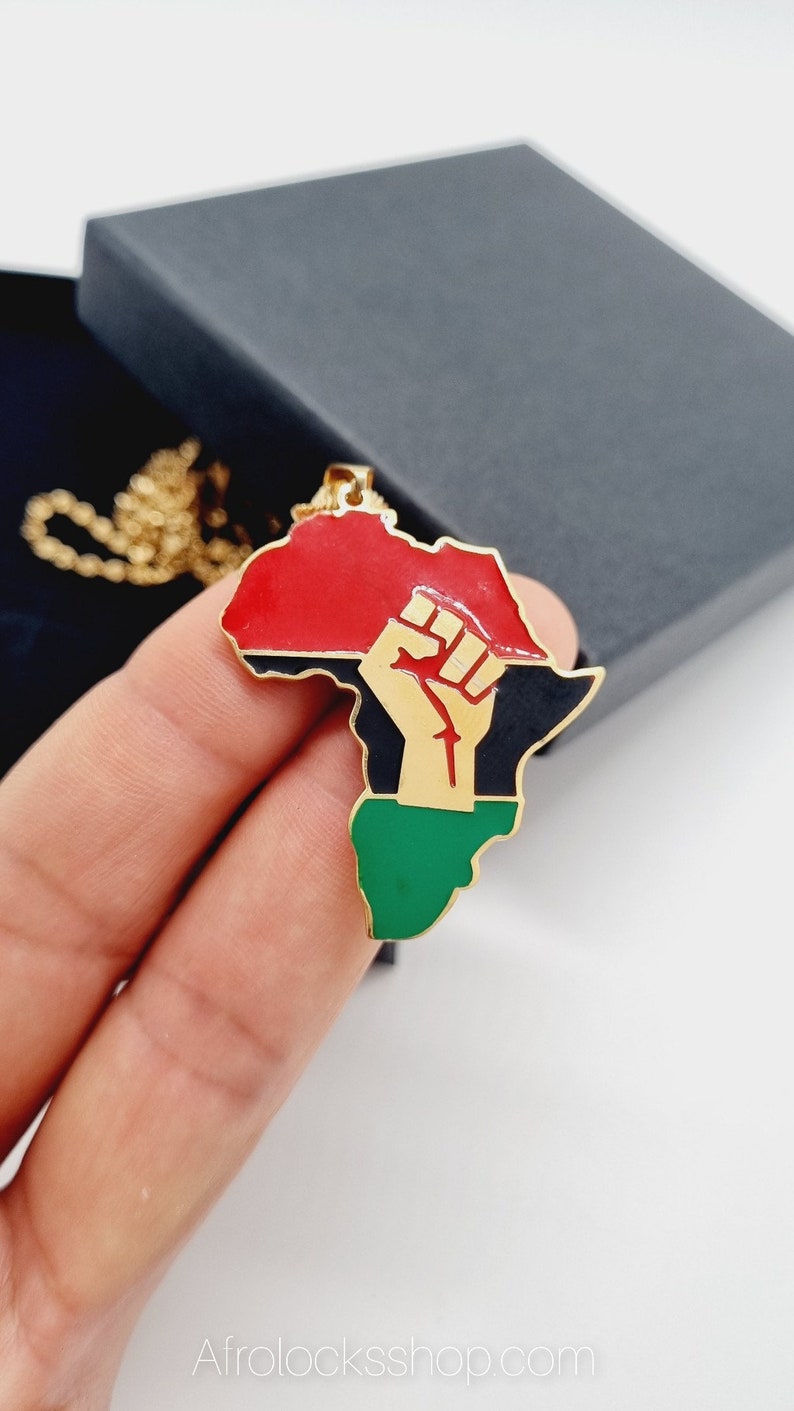 K&ouml;nnte beinhalten: Goldkette mit einem Anh&auml;nger in Form des afrikanischen Kontinents. Der Anh&auml;nger ist in den Farben der panafrikanischen Flagge bemalt: rot, schwarz und gr&uuml;n. Eine erhobene goldene Faust befindet sich in der Mitte des Anh&auml;ngers.