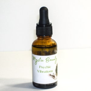 May include: A brown glass bottle with a black dropper top. The bottle is labeled "Mystic Bounty Psychic Vibrations" with a green leaf design.