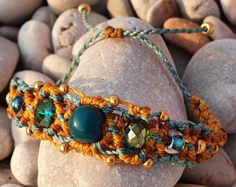 Puede incluir: Pulsera de macramé hecha a mano, en tonos turquesa y dorado. Presenta una piedra central turquesa, rodeada de pequeñas cuentas verdes y azules, y detalles dorados. El cordón ajustable es turquesa.