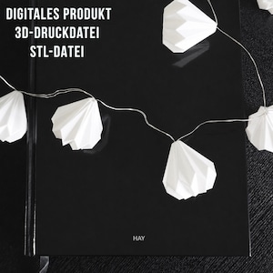 Könnte beinhalten: Ein schwarzes Notizbuch mit dem Wort "HAY" unten rechts. Eine Lichterkette aus weißen Papierlaternen ist über das Notizbuch drapiert. Der Text "DIGITALES PRODUKT 3D-DRUCKDATEI STL-DATEI" ist oben links gedruckt.