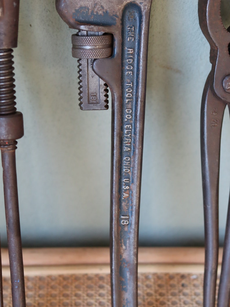 Może przedstawiać: Zbliżenie na zardzewiały klucz do rur z wygrawerowanym tekstem "THE RIDGE TOOL CO. ELYRIA OHIO U.S.A. 1/8". Klucz ma oznaczenie rozmiaru 3,2 mm.