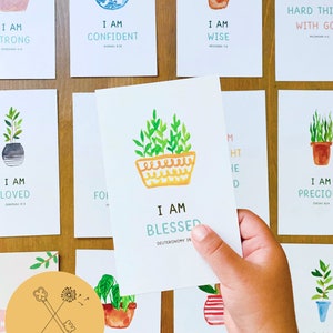 May include: A set of 10 printable cards featuring watercolor illustrations of potted plants with inspirational quotes and bible verses. The cards are designed in a light and cheerful style with a yellow, green, and blue color scheme. The text on the cards includes phrases like "I am strong", "I am confident", "I am wise", "I am loved", "I am blessed", "I am precious", "I am protected", "I am chosen", and "I am not afraid".