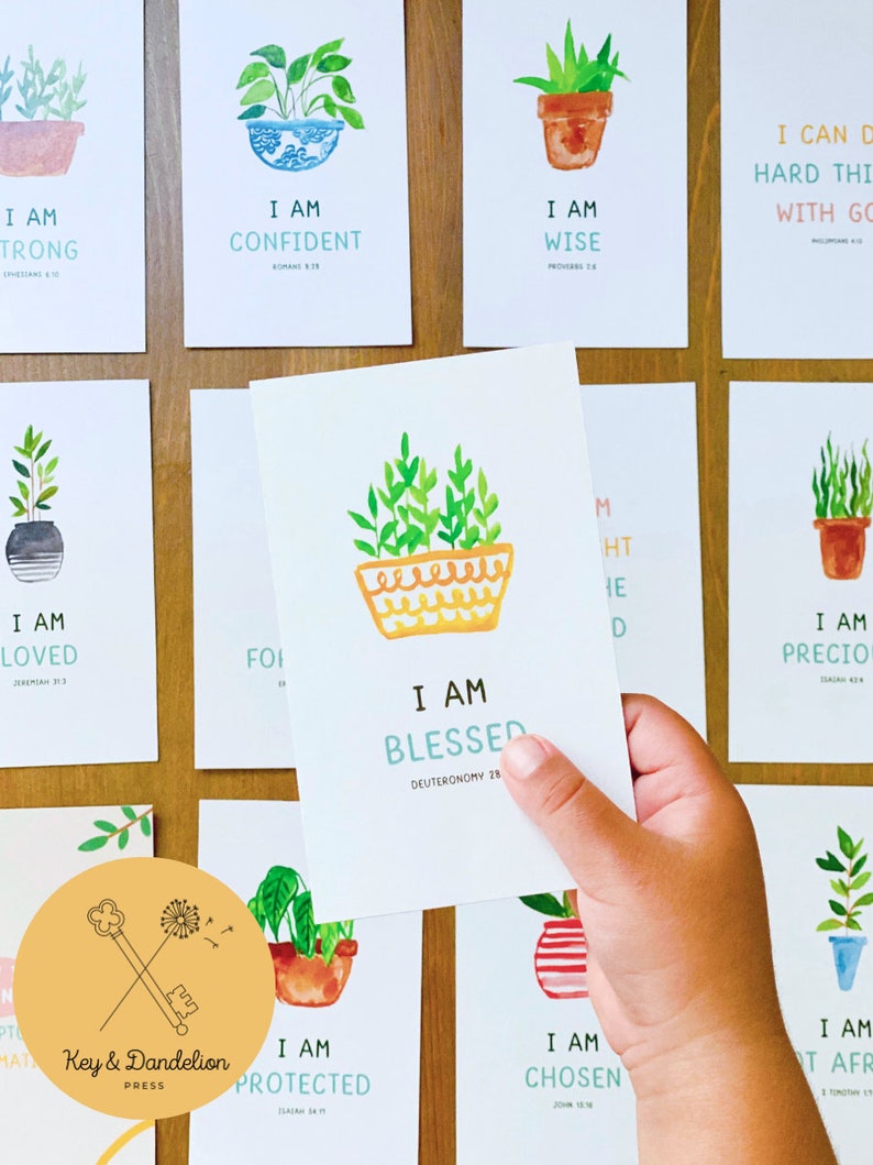 May include: A set of 10 printable cards featuring watercolor illustrations of potted plants with inspirational quotes and bible verses. The cards are designed in a light and cheerful style with a yellow, green, and blue color scheme. The text on the cards includes phrases like "I am strong", "I am confident", "I am wise", "I am loved", "I am blessed", "I am precious", "I am protected", "I am chosen", and "I am not afraid".