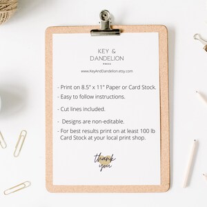 May include: A white clipboard with a cork backing, featuring instructions for printing a printable design. The text reads: "Print on 8.5" x 11" Paper or Card Stock. Easy to follow instructions. Cut lines included. Designs are non-editable. For best results print on at least 100 lb Card Stock at your local print shop. Thank you."