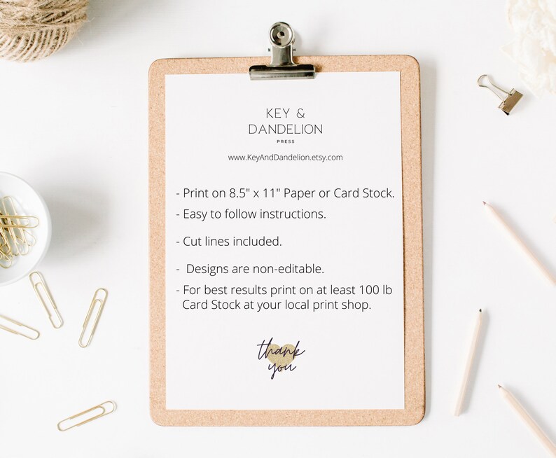 May include: A white clipboard with a cork backing, featuring instructions for printing a printable design. The text reads: "Print on 8.5" x 11" Paper or Card Stock. Easy to follow instructions. Cut lines included. Designs are non-editable. For best results print on at least 100 lb Card Stock at your local print shop. Thank you."