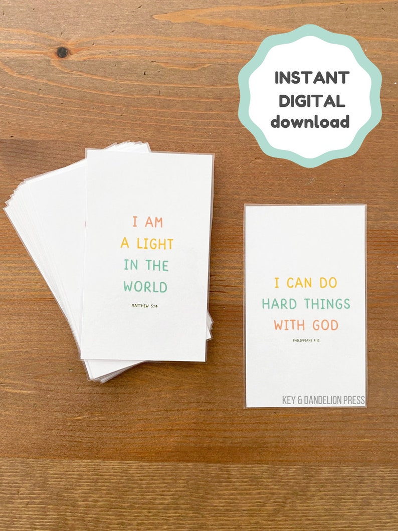 May include: Two printable cards with inspirational quotes and bible verses. The first card is white with the text "I am a light in the world" and the bible verse "Matthew 5:14". The second card is white with the text "I can do hard things with God" and the bible verse "Philippians 4:13". Both cards have a colorful design with a key and dandelion logo at the bottom.