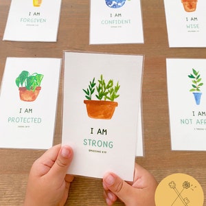 Könnte beinhalten: Satz mit 6 Affirmationskarten mit Aquarell-Illustrationen von Topfpflanzen. Jede Karte zeigt eine positive Affirmation und einen Bibelvers. Die Karten sind auf weißem Karton gedruckt und haben abgerundete Ecken.