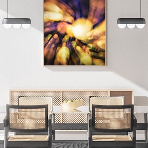 May include: A dining room with a wooden table and chairs. The table has a woven rattan back and seat. The chairs are black with woven rattan backs and seats. A framed abstract painting with a yellow, orange, and purple color scheme hangs on the wall above the table.