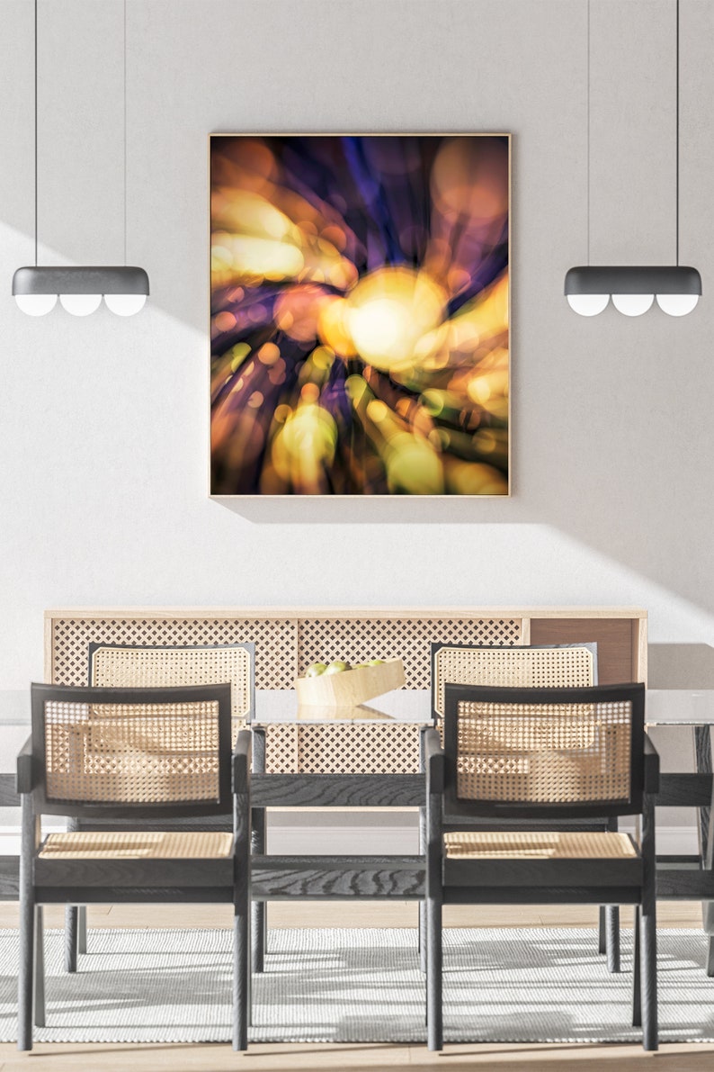 May include: A dining room with a wooden table and chairs. The table has a woven rattan back and seat. The chairs are black with woven rattan backs and seats. A framed abstract painting with a yellow, orange, and purple color scheme hangs on the wall above the table.