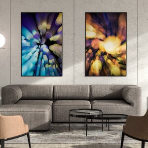 May include: Two abstract art prints with a blurred, colourful, and circular design. The prints are framed in black and hung on a grey concrete wall above a grey sectional sofa.