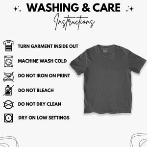 May include: A charcoal gray t-shirt with washing instructions. The text reads: Turn garment inside out, machine wash cold, do not iron on print, do not bleach, do not dry clean, and dry on low settings.