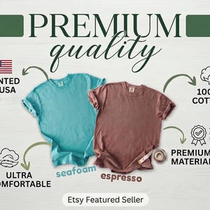 May include: Two short-sleeved t-shirts, one seafoam and one espresso, are displayed on a light wood-grain background. The text "PREMIUM quality" is at the top. Additional text includes "PRINTED IN USA", "100% COTTON", "ULTRA COMFORTABLE", and "PREMIUM MATERIAL".