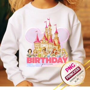 Puede incluir: Sudadera blanca con una colorida ilustración de un castillo, princesas y el texto "BIRTHDAY princess". El diseño incluye tonos rosas, dorados y azules. Un gráfico PNG Princess circular está en la esquina inferior derecha.