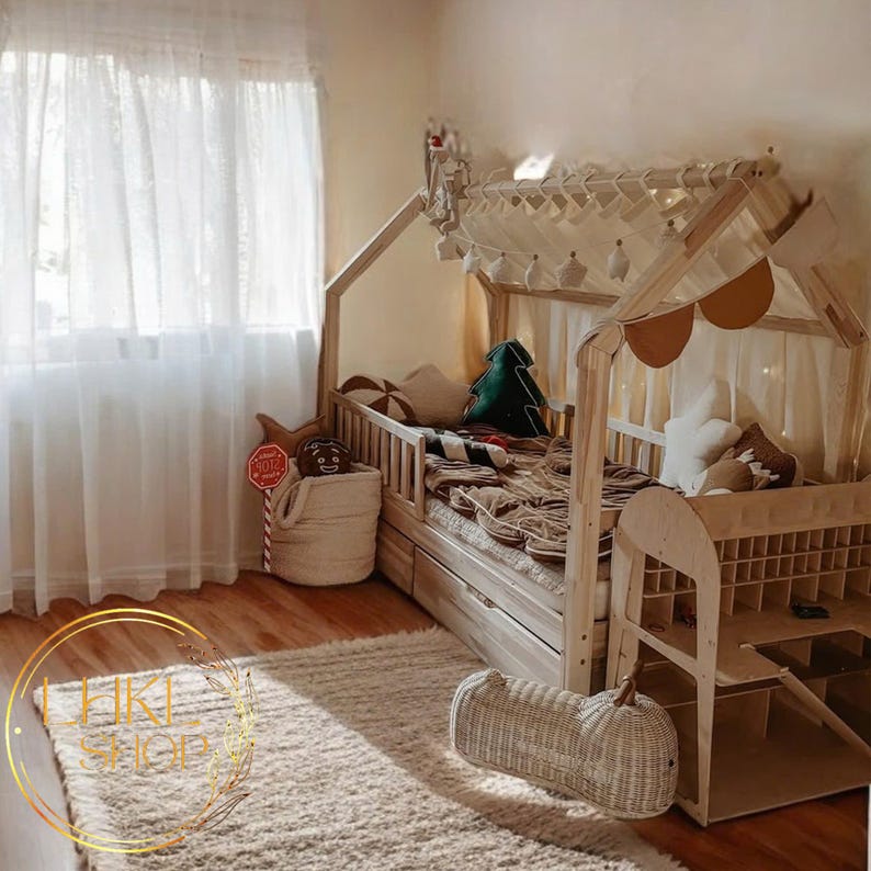 May include: A wooden bed frame shaped like a house with a white canopy and a white and brown patterned blanket. The bed has a built-in storage drawer and a ladder on the side. The bed is in a room with a white curtain and a rug on the floor.