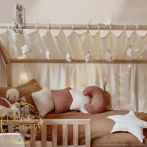 May include: A wooden bed frame with a white canopy and a brown and white bedding set. The bed is decorated with a string of star-shaped decorations and several plush pillows.