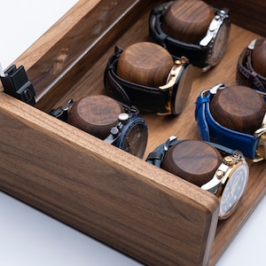 Puede incluir: Una caja de madera para relojes con tapa de cristal, que incluye seis remontadores de relojes con correas de diferentes colores. La caja est&aacute; hecha de madera oscura con veta natural.