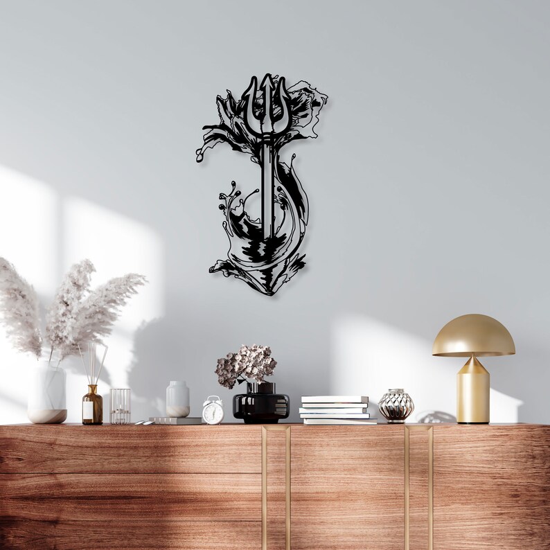 May include: Black metal wall art depicting a trident piercing through a wave of water. The art piece is mounted on a white wall above a wooden shelf with decorative items.
