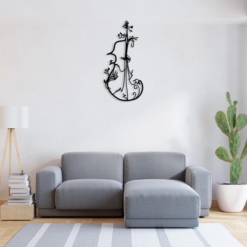 May include: Black metal wall art sculpture of a violin with intricate floral details. The sculpture is mounted on a white wall above a grey sofa.