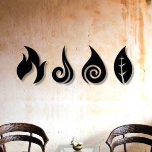 May include: Four black metal wall decor pieces in the shape of stylised elements: fire, water, air, and earth. The elements are arranged horizontally on a light beige wall.