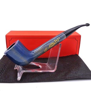 May include: A blue smoking pipe with a black stem, resting on a clear stand. The pipe has the word "Jazz" and a trumpet design in gold. A red box is in the background.