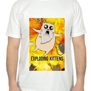 May include: White t-shirt featuring a cartoon graphic from the game Exploding Kittens. The graphic shows a surprised cat with a long white beard against a yellow and orange explosion background. The words "EXPLODING KITTENS" are printed below the cat.
