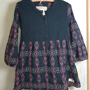 May include: A black long-sleeved dress with a gathered bodice and embroidered floral pattern in pink and cream.