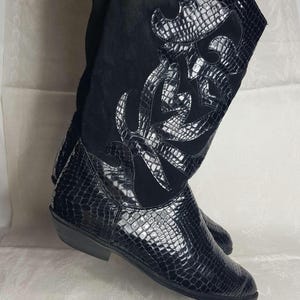 May include: Black knee-high boots with a snakeskin pattern and a floral design on the side.