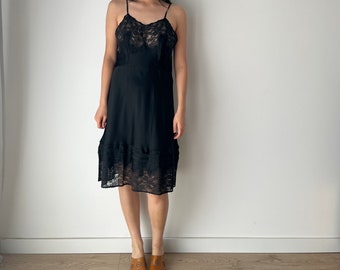Peut inclure: Une robe de nuit noire en dentelle avec une femme qui la porte. Elle porte des chaussures en cuir marron avec des boucles décoratives.