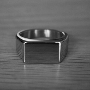 May include: A silver signet ring with a square top.