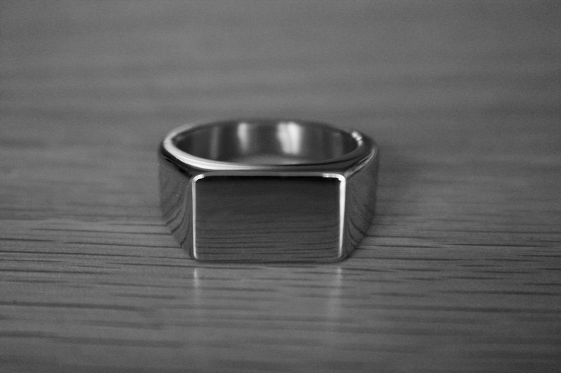May include: A silver signet ring with a square top.