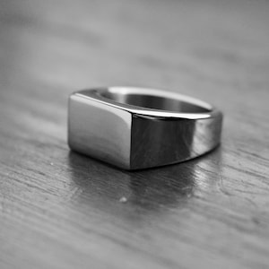 May include: A silver signet ring with a rectangular top.