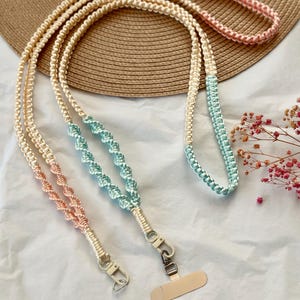 May include: A set of three colourful braided lanyards with a cream, pink and teal colour scheme. Each lanyard has a metal clasp and a clear plastic badge holder.