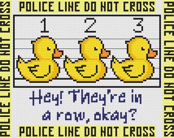Puede incluir: Un pato de goma amarillo con un cartel de "Police Line Do Not Cross" encima. El pato está en una fila con otros dos patos. El texto debajo de los patos dice "Hey! They're in a row, okay?"