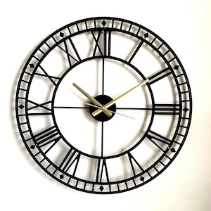 May include: Black metal wall clock with Roman numeral markings and gold-coloured hands.