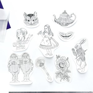 Può includere: Un set di dieci trasferimenti a caldo in bianco e nero a tema Alice nel Paese delle Meraviglie. I trasferimenti presentano personaggi come il Cappellaio Matto, il Gatto del Cheshire e la Regina di Cuori.
