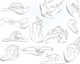 May include: A set of 12 black and white line art tattoo designs on white paper. The designs include a wave, a lightbulb, a monstera leaf, a dragon, a bird, a hand, a woman, a lips, an owl, a cat, and a fish.