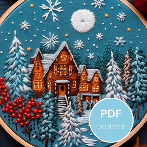 May include: Embroidered hoop art featuring a cozy winter scene with a house, trees, and a snowy night sky. The design includes a large moon, snowflakes, and a small house with glowing windows. The hoop is made of wood and has a blue fabric background.