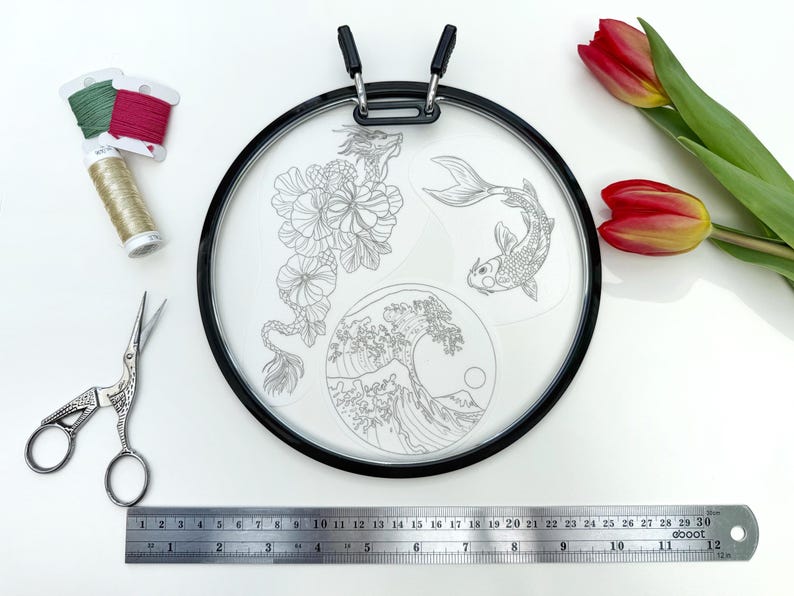 May include: A round embroidery hoop with a black frame, featuring a dragon, koi fish, and wave design. Includes embroidery floss, scissors, and a 12-inch ruler. Red and yellow tulips are also present.