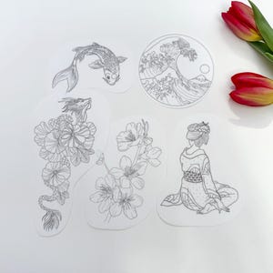 Könnte beinhalten: Fünf transparente Aufkleber mit schwarzen Strichzeichnungen. Die Designs umfassen einen Koi-Karpfen, eine Welle in einem Kreis, einen Drachen mit Blumen, Kirschblüten und eine Geisha. Zwei rot-gelbe Tulpen befinden sich in der oberen rechten Ecke.