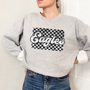 May include: Gray sweatshirt with a black and white checkered design and the word "Eagles" in a retro font.